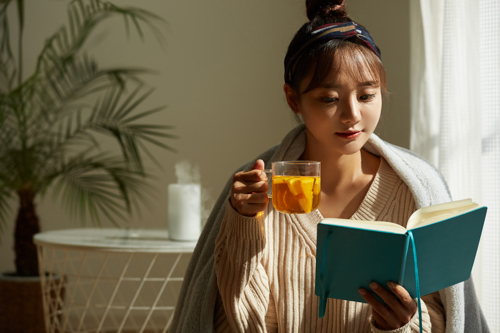 Woman reading book with cup of tea