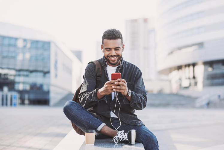 Man smiling at phone in city centre